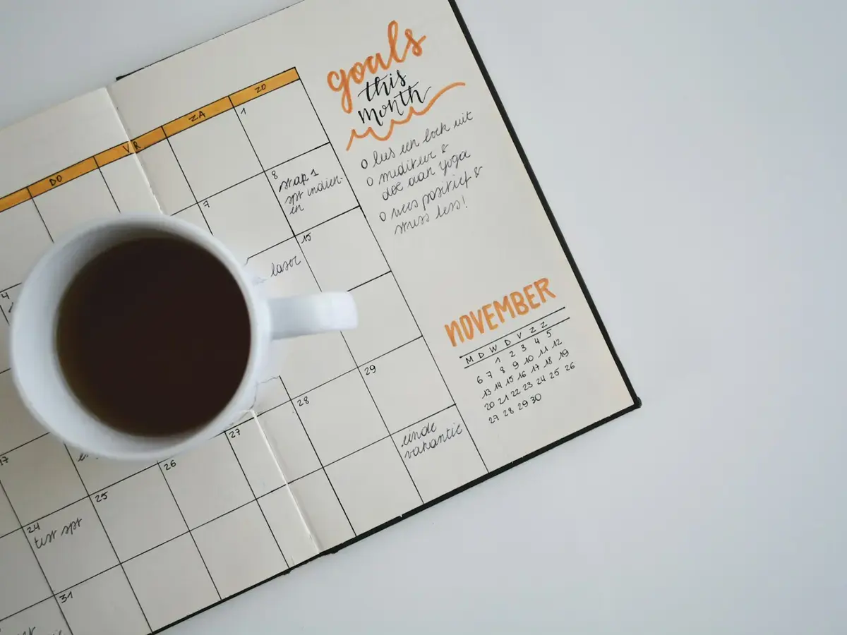 Monthly planner spread with goals and appointments beside a cup of coffee